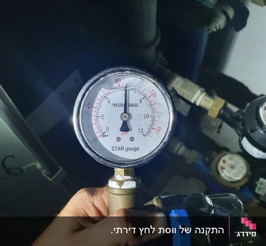 מד לחץ מים מוחזק ביד של אינסטלטור
